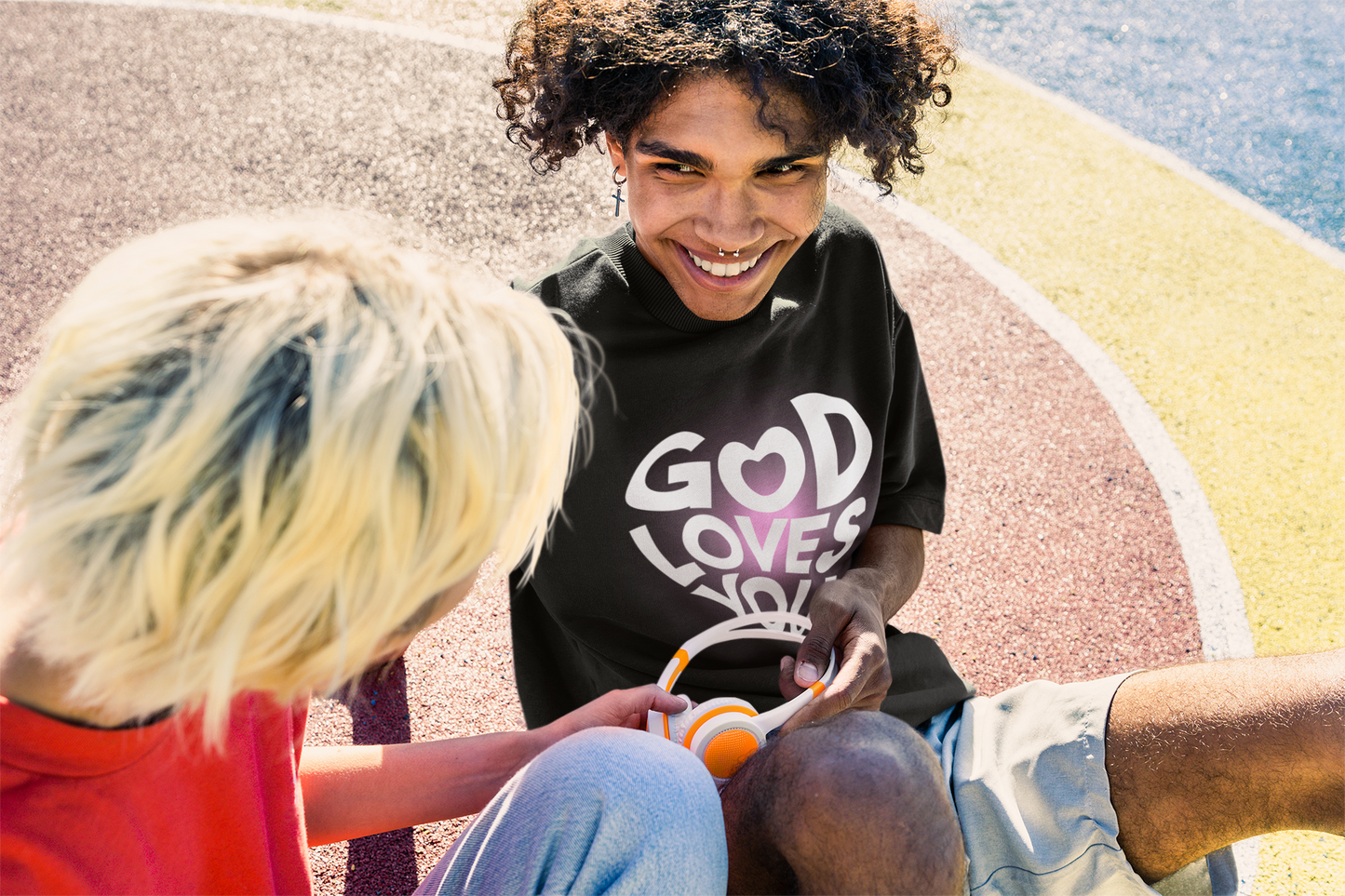 A man wearing "God Loves You" unisex oversized black t-shirt at front view. Unique fashion tops - cute Y2k, good vibe tee. Front and back printed - Oh Mine Words