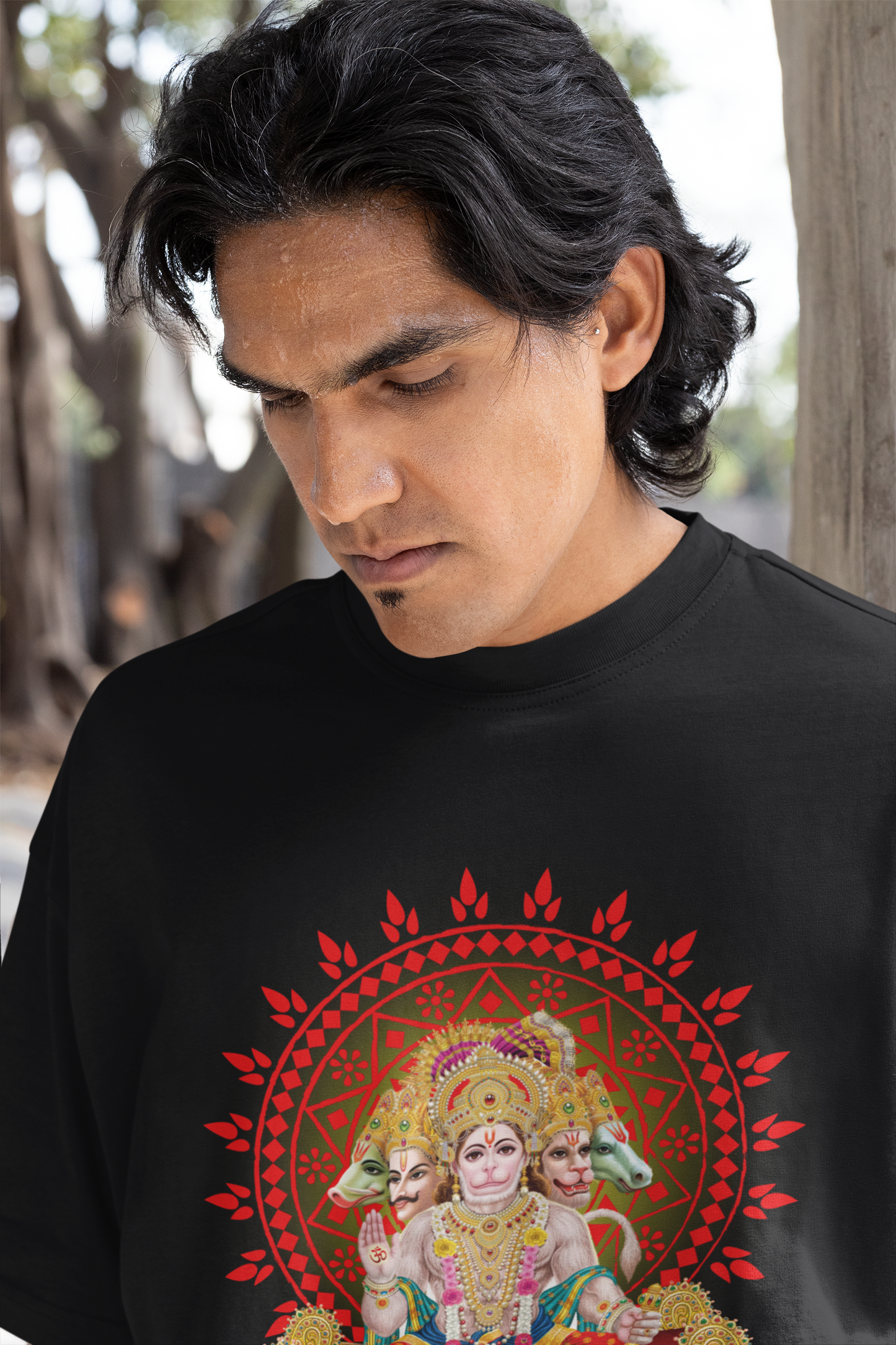 A man wearing "Hanuman Ji" unisex oversized black T-shirt at close-up front view. Unique fashion tops - wear comfy, chic and cool with God and Religious graphic. Front and back printed - Oh Mine Words