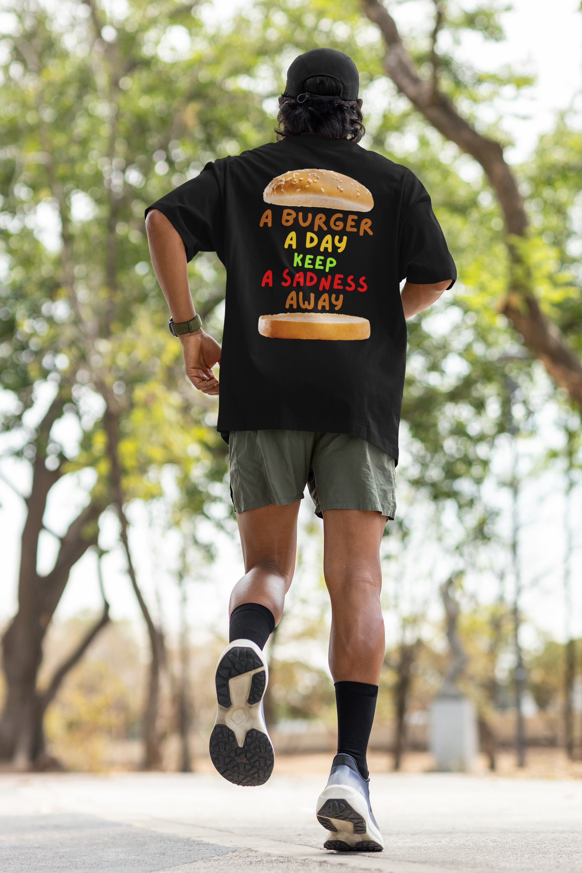 A man wearing unisex oversized "A Burger A Day Keep A Sadness Away" black t-shirt, back view - unique fashion tops - funny quote, buns, burger, foodie, comfortable, front and back print - Oh Mine Words.