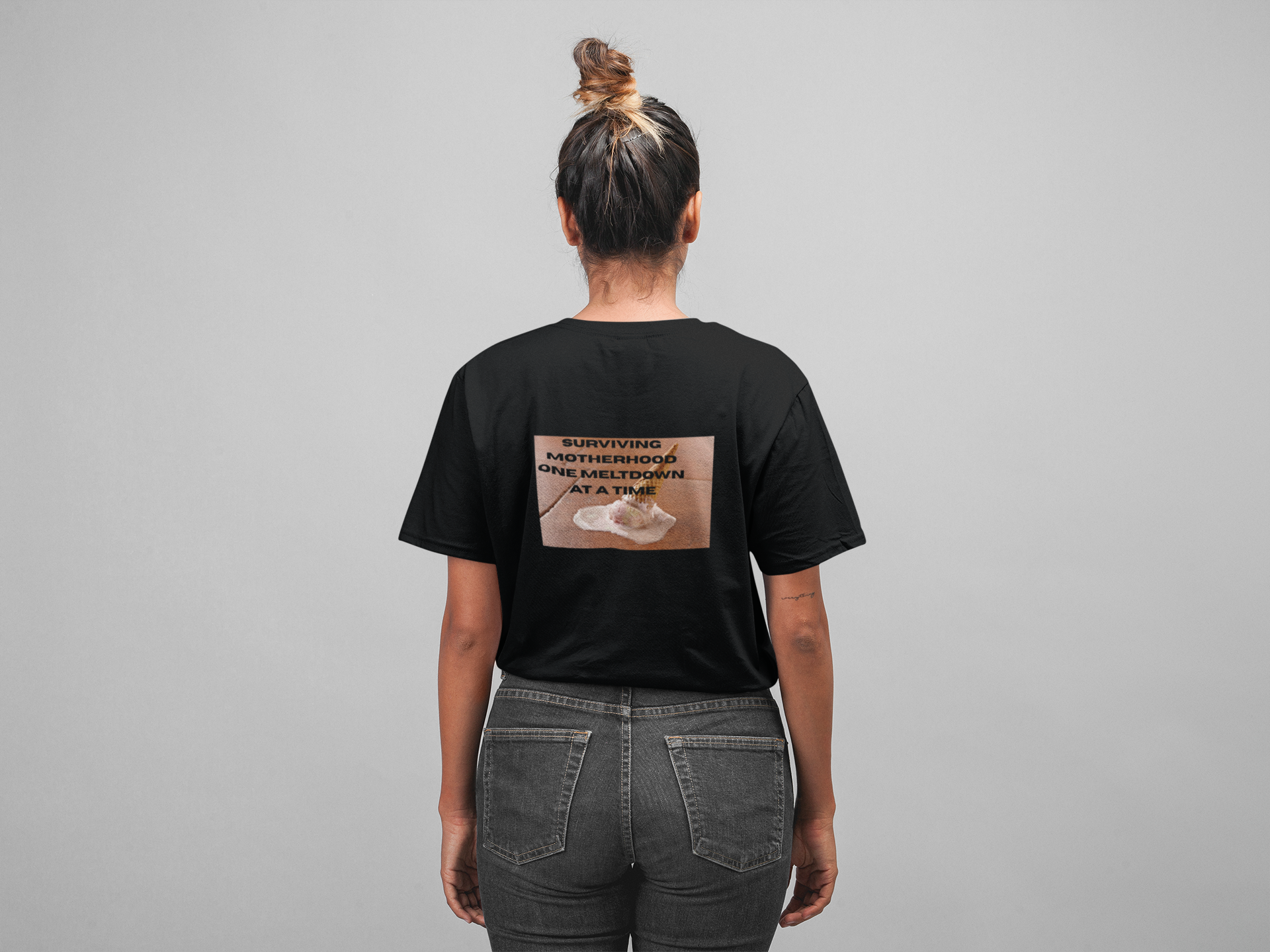 A women wearing unisex oversized "Surviving Motherhood One Meltdown At A Time (Full-Black)" t-shirt at back view - unique fashion tops, funny quote, Ice cream melt down for A Mom and Mother's day - Front and Back Print - Oh Mine Words.
